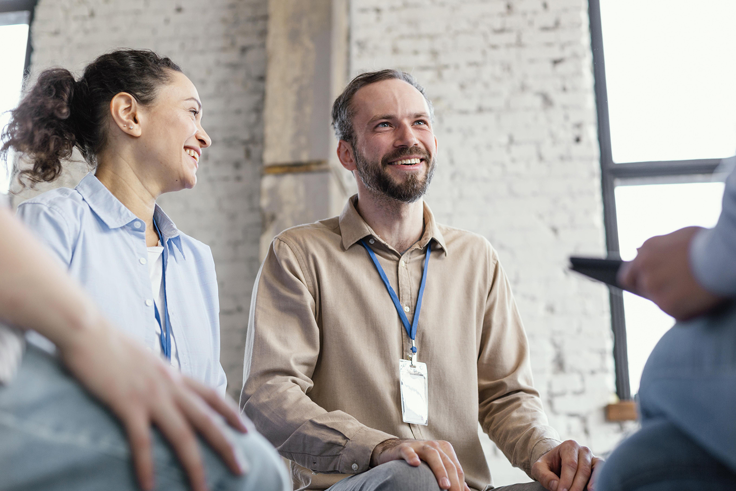 Two colleagues smiling and engaged in conversation in a bright industrial-style office